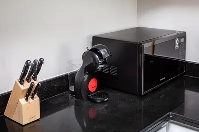 a black microwave sitting on a counter next to some knives at Modern 1BR apartment Artesia DAMAC Hills in Dubai