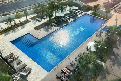 an overhead view of a large swimming pool with palm trees at Modern 1BR apartment Artesia DAMAC Hills in Dubai