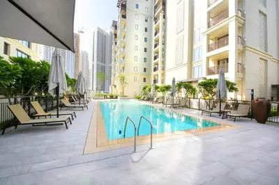 a swimming pool with chairs and umbrellas next to a building at Breeze haven residences- 2BHK brand new furnished apartment in Dubai