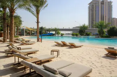a beach with lounge chairs and a swimming pool at Breeze haven residences- 2BHK brand new furnished apartment in Dubai