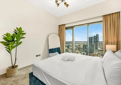 a bedroom with a white bed and a large window at Burj Royale Dubai Downtown in Dubai