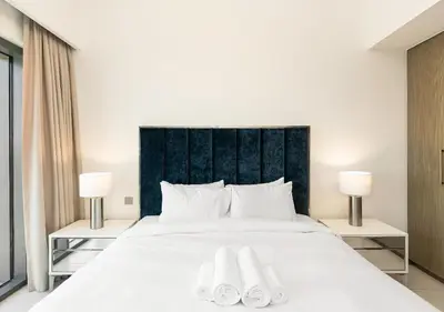 a bedroom with a large white bed with two lamps at Burj Royale Dubai Downtown in Dubai