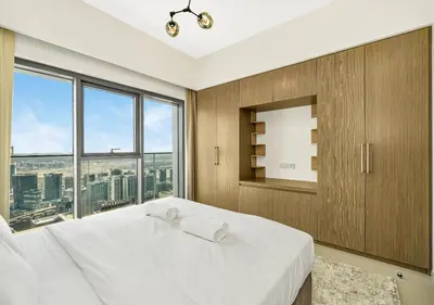 a bedroom with a large white bed with a large window at Burj Royale Dubai Downtown in Dubai