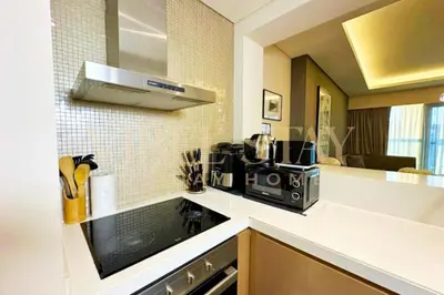 a kitchen with a stove top oven next to a microwave at Prime 1BR Location Minutes to Burj Dubai Mall by Vibel in Dubai