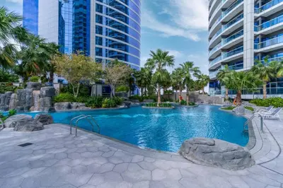 a swimming pool in a resort with palm trees and buildings at Prime 1BR Location Minutes to Burj Dubai Mall by Vibel in Dubai