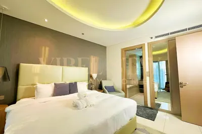 a bedroom with a large white bed with towels on it at Prime 1BR Location Minutes to Burj Dubai Mall by Vibel in Dubai
