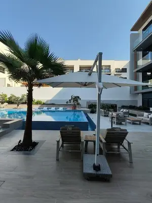 a pool with a table and an umbrella and chairs at Stylish Boutique Loft Duplex, Near Circle Mall, Balcony, Fast WiFi, 2 Pools and Gym in Dubai
