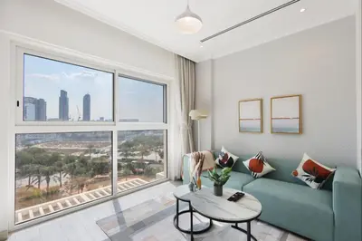 a living room with a blue couch and a large window at Livbnb-Modern Living 1B Apartment in JVC in Dubai
