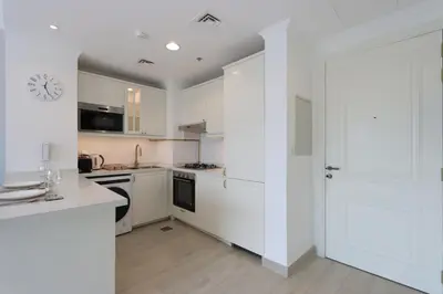 a kitchen with white cabinets and a clock on the wall at Livbnb-Modern Living 1B Apartment in JVC in Dubai