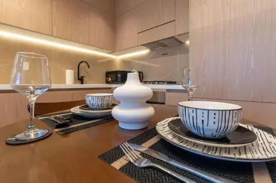 a wooden table with plates and wine glasses on it at Urban Studio With Pool & Tennis Court in Dubai