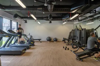 two people in a gym with treadmills and machines at Urban Studio With Pool & Tennis Court in Dubai