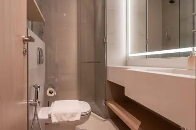 a bathroom with a toilet and a sink and a mirror at Urban Studio With Pool & Tennis Court in Dubai