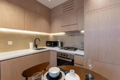 a kitchen with wooden cabinets and a table with a table at Urban Studio With Pool & Tennis Court in Dubai