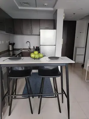 a kitchen with two bar stools and a counter with fruit on it at Lake & Beach view Studio in the Center of Marina in Dubai