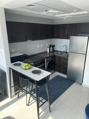a kitchen with a table with a bowl of fruit on it at Lake & Beach view Studio in the Center of Marina in Dubai