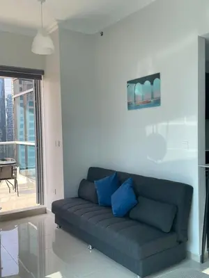 a couch in a living room with a large window at Lake & Beach view Studio in the Center of Marina in Dubai