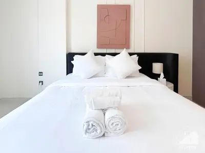 a bedroom with a white bed with towels on it at Stylish Escape in Meydan 1B Polo Residence C3 in Dubai