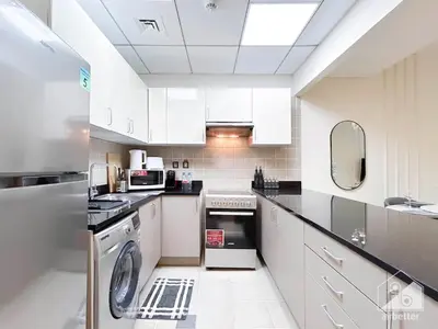 a kitchen with white cabinets and a washer and dryer at Stylish Escape in Meydan 1B Polo Residence C3 in Dubai