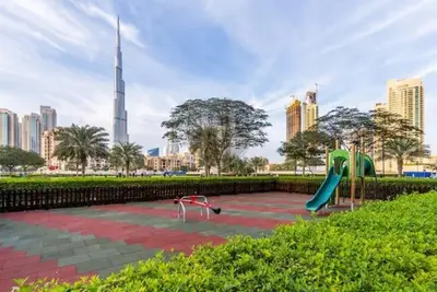 a playground in a park with a tall building at Vogue Business Bay Damac Maison Prive near Burj Khalifa and Dubai Mall, Studio Apartment with Canal and City View, Access to all Amenities in Dubai