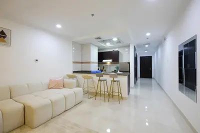 a living room with a white couch and a kitchen at Spectacular Studio & 1 Bedroom Units By Costa close to metro in Dubai