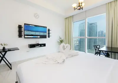 a white bedroom with a bed with a towel animal on it at Spectacular Studio & 1 Bedroom Units By Costa close to metro in Dubai