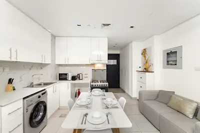 a kitchen and living room with a table and a couch at Studio Dubai, Cozy Luxury Stay Near Downtown Dining Shopping & Leisure in Dubai