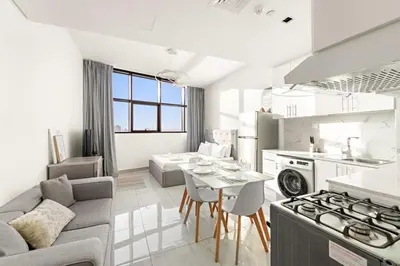 a kitchen and living room with a couch and a table at Studio Dubai, Cozy Luxury Stay Near Downtown Dining Shopping & Leisure in Dubai