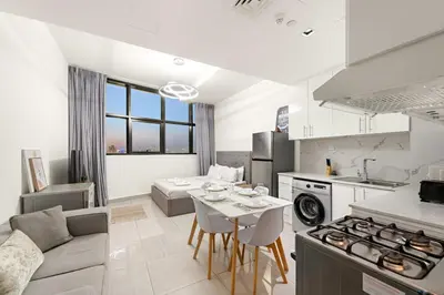 a kitchen and living room with a couch and a table at Studio Dubai, Cozy Luxury Stay Near Downtown Dining Shopping & Leisure in Dubai