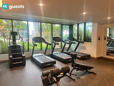 a gym with several tread machines in a room with windows at HiGuests - Modern & Stylish 1BR Apt - Near Business Bay Metro in Dubai
