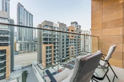 a balcony with chairs and a view of a city at City View Studio Minutes Drive to Burj Khalifa, Azizi Riviera 43, Al Merkadh by Deluxe Holiday Homes in Dubai