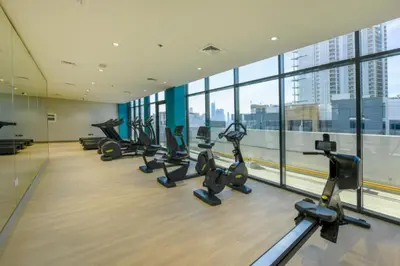 a gym with a row of treadmills and ellipticals at City View Studio Minutes Drive to Burj Khalifa, Azizi Riviera 43, Al Merkadh by Deluxe Holiday Homes in Dubai