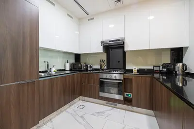 a large kitchen with wooden cabinets and appliances at Cozy 1BR with Canal View, Pool & Gym Access in Dubai