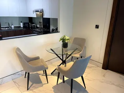 a dining room with a glass table and chairs at Cozy 1BR with Canal View, Pool & Gym Access in Dubai