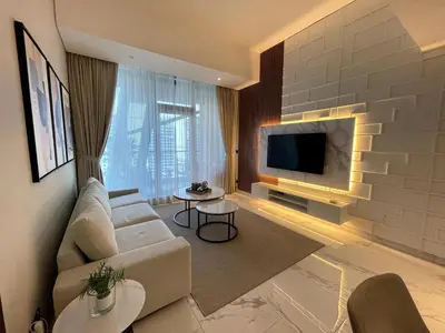 a living room with a couch and a tv at Cozy 1BR with Canal View, Pool & Gym Access in Dubai