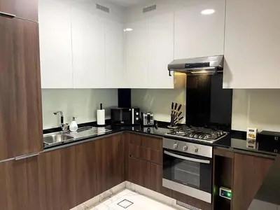 a kitchen with white cabinets and a stove top oven at Cozy 1BR with Canal View, Pool & Gym Access in Dubai