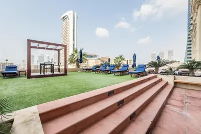 a rooftop patio with chairs and a table and grass at Renovated Unit with Skyscraper Views, Close to JBR Beach, Elite Residence, Dubai Marina by Deluxe Holiday Homes in Dubai