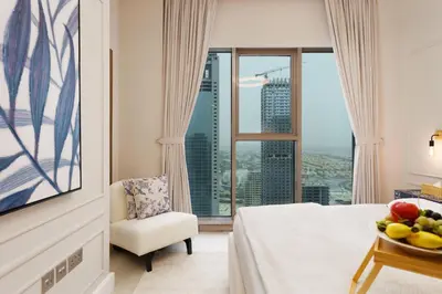a hotel room with a bed and a chair and a window at Maison Privee - Modern Living with Premium Amenities close to Marina in Dubai
