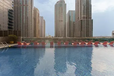 a large swimming pool with red chairs in a city at Maison Privee - Modern Living with Premium Amenities close to Marina in Dubai