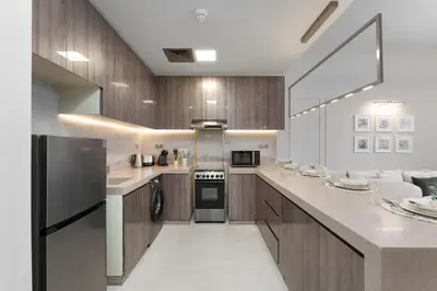 a kitchen with white counter tops and wooden cabinets at Maison Privee - Modern Living with Premium Amenities close to Marina in Dubai