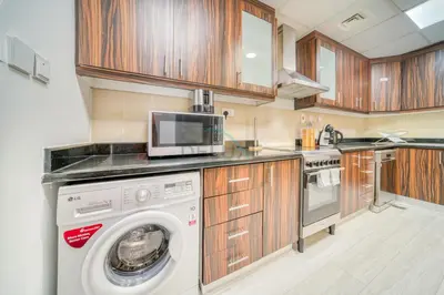 a kitchen with a washing machine and a microwave at High Floor 2BR With a View of the Dubai Marina Canal Steps Away From the Beach , Shams 1, JBR by Deluxe Holiday Homes in Dubai