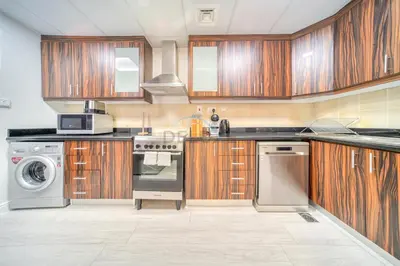a kitchen with wooden cabinets and a washer and dryer at High Floor 2BR With a View of the Dubai Marina Canal Steps Away From the Beach , Shams 1, JBR by Deluxe Holiday Homes in Dubai