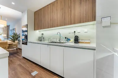 a kitchen with white cabinets and a dining room at Refurbished 1BR High-Floor Unit with Partial City & Sea Views, Walking Distance to the Beach, Elite Residence, Dubai Marina by Deluxe Holiday Homes in Dubai