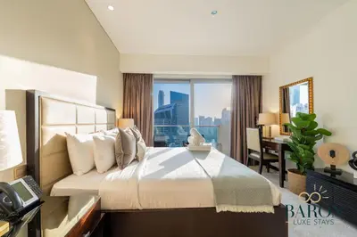 a hotel room with a bed and a desk and a window at The Exquisite in Dubai