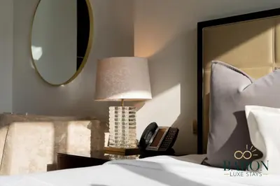 a bedroom with a bed with a lamp and a phone at The Exquisite in Dubai
