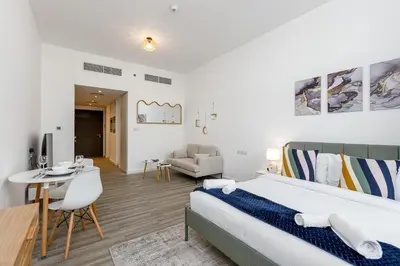 a bedroom with a bed and a living room at Upgraded Brand New Studio in Belgravia 2, JVC - Allsopp & Allsopp in Dubai