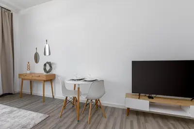 a living room with a tv and a table and chairs at Upgraded Brand New Studio in Belgravia 2, JVC - Allsopp & Allsopp in Dubai
