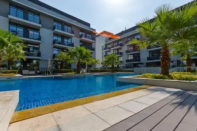 a swimming pool with palm trees in front of a building at Upgraded Brand New Studio in Belgravia 2, JVC - Allsopp & Allsopp in Dubai