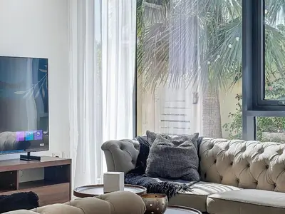 a living room with a couch and a television at Modern Five Bedroom Villa with BBQ and Garden in Dubai