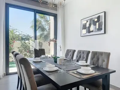a dining room with a table and chairs and a window at Modern Five Bedroom Villa with BBQ and Garden in Dubai