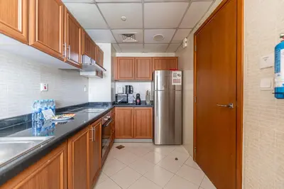 a kitchen with wooden cabinets and a stainless steel refrigerator at HAVN - 2-Storey Apartment with Dubai Marina Views in Dubai
